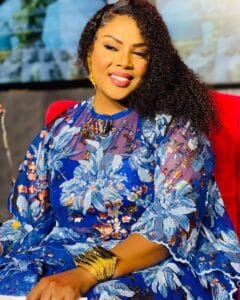 En tunique bleue, Amina Poté sourit de resplendissement